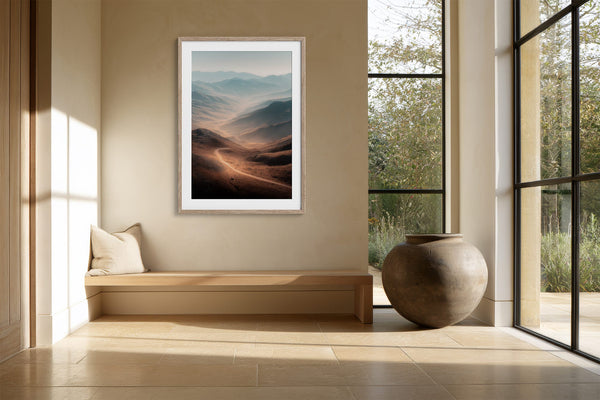 Light wood-framed mountain valley artwork above a built-in bench beside a large ceramic vessel.