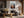 Light wood-framed mountain valley artwork above a gray sofa beneath exposed wooden beams.