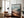 Large black-framed mountain valley artwork leaning beside a leather armchair and floor lamp.