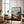 Large black-framed mountain valley artwork leaning beside a leather armchair and floor lamp.