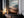 Large thin-framed mountain valley artwork leaning on a dark cabinet beside lit candles.