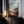 Large thin-framed mountain valley artwork leaning on a dark cabinet beside lit candles.