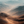 Winding track through a sunlit mountain pass beneath layered blue-grey peaks